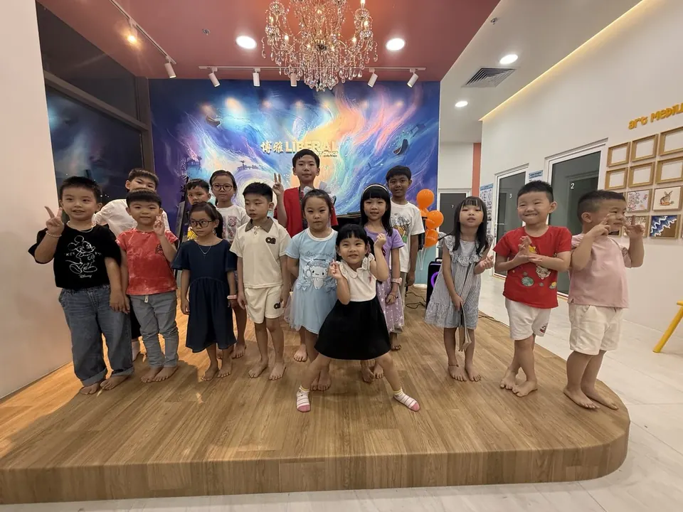 Young piano students smiling on the stage at Liberal Music & Arts School's Tengah HQ