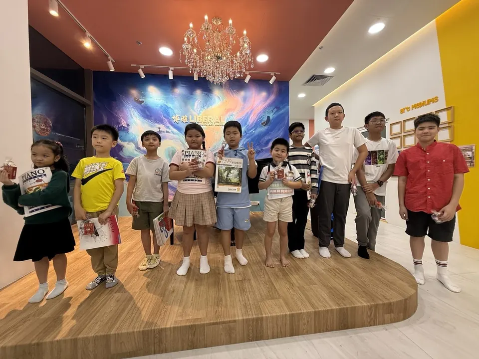 Piano students holding their books and gifts on the Tengah HQ stage